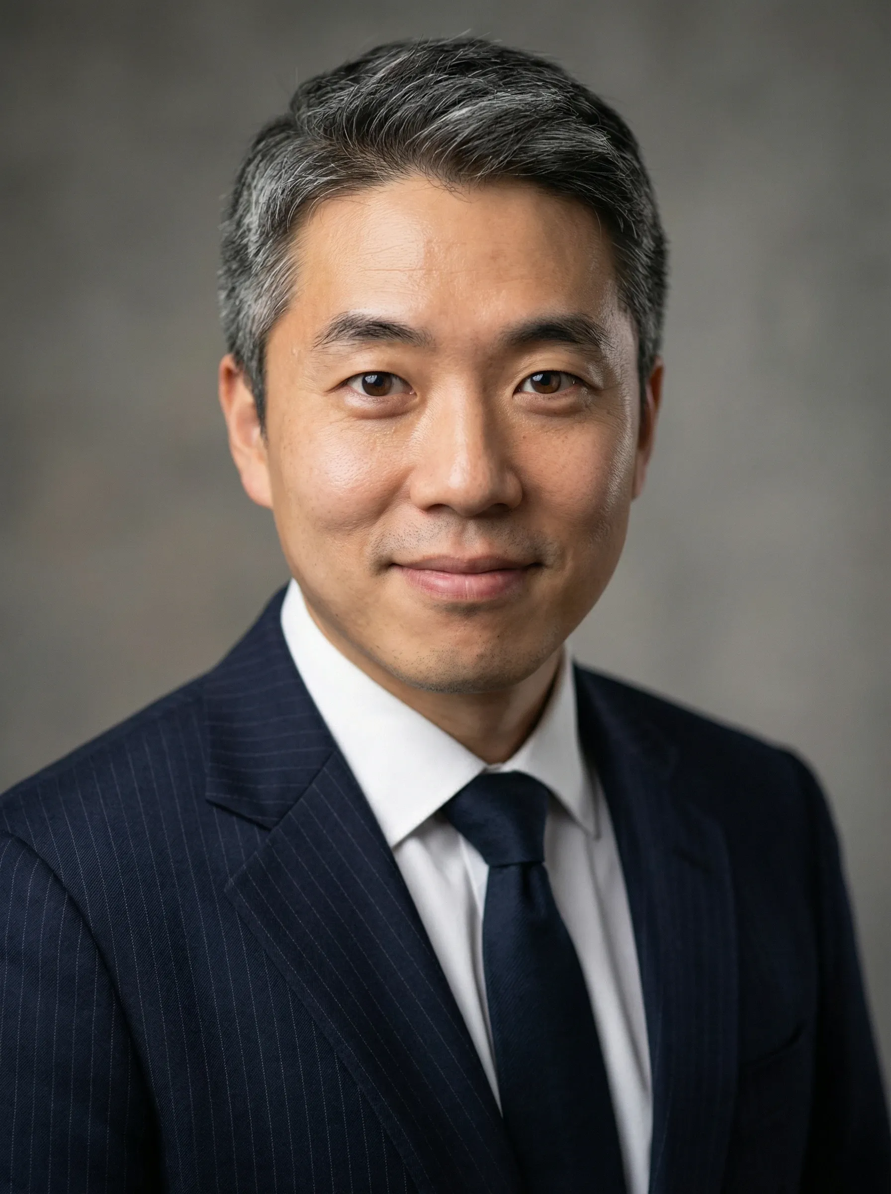 AI LinkedIn headshot — man in a navy pinstripe suit and dark tie against a studio backdrop
